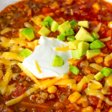 Close-up of a hearty meatless vegetarian chili bowl with toppings like shredded cheese, sour cream, and fresh avocado, perfect for game day or a cozy meal.