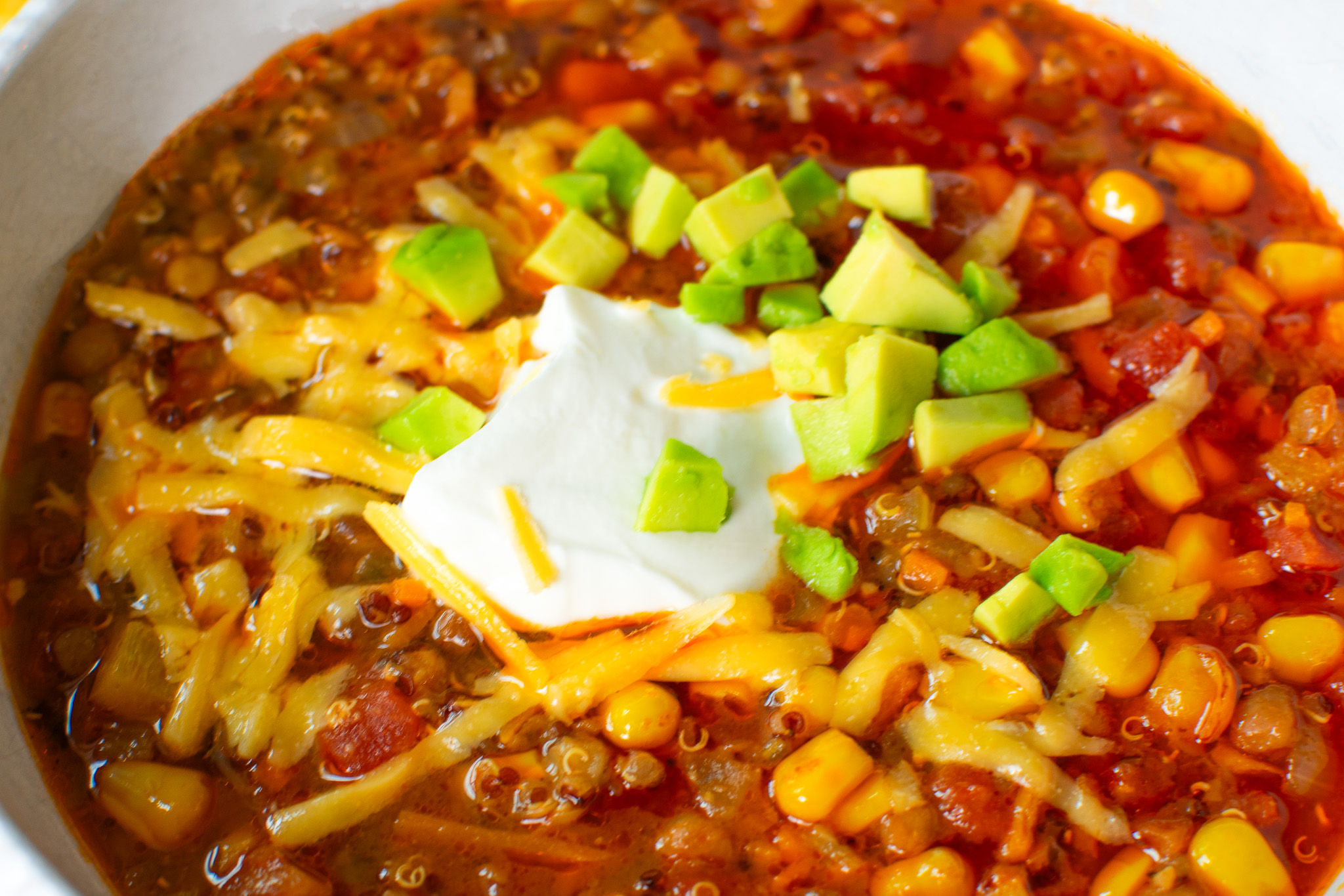 Meatless vegetarian chili with sour cream, cheddar cheese and avocado