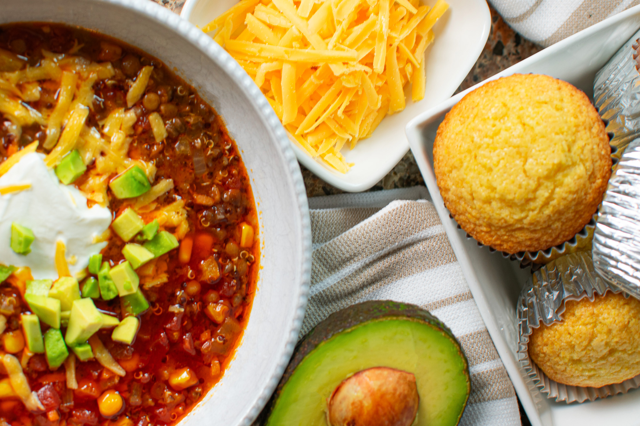 Meatless vegetarian chili with corn muffin, shredded cheddar cheese, and fresh avocado