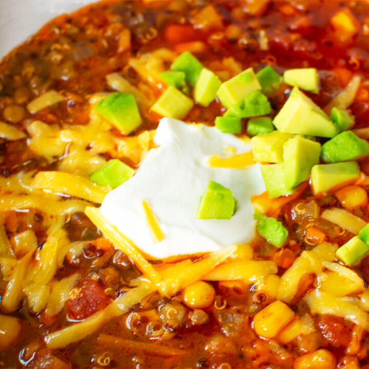 Close-up of a hearty meatless vegetarian chili bowl with toppings like shredded cheese, sour cream, and fresh avocado, perfect for game day or a cozy meal.