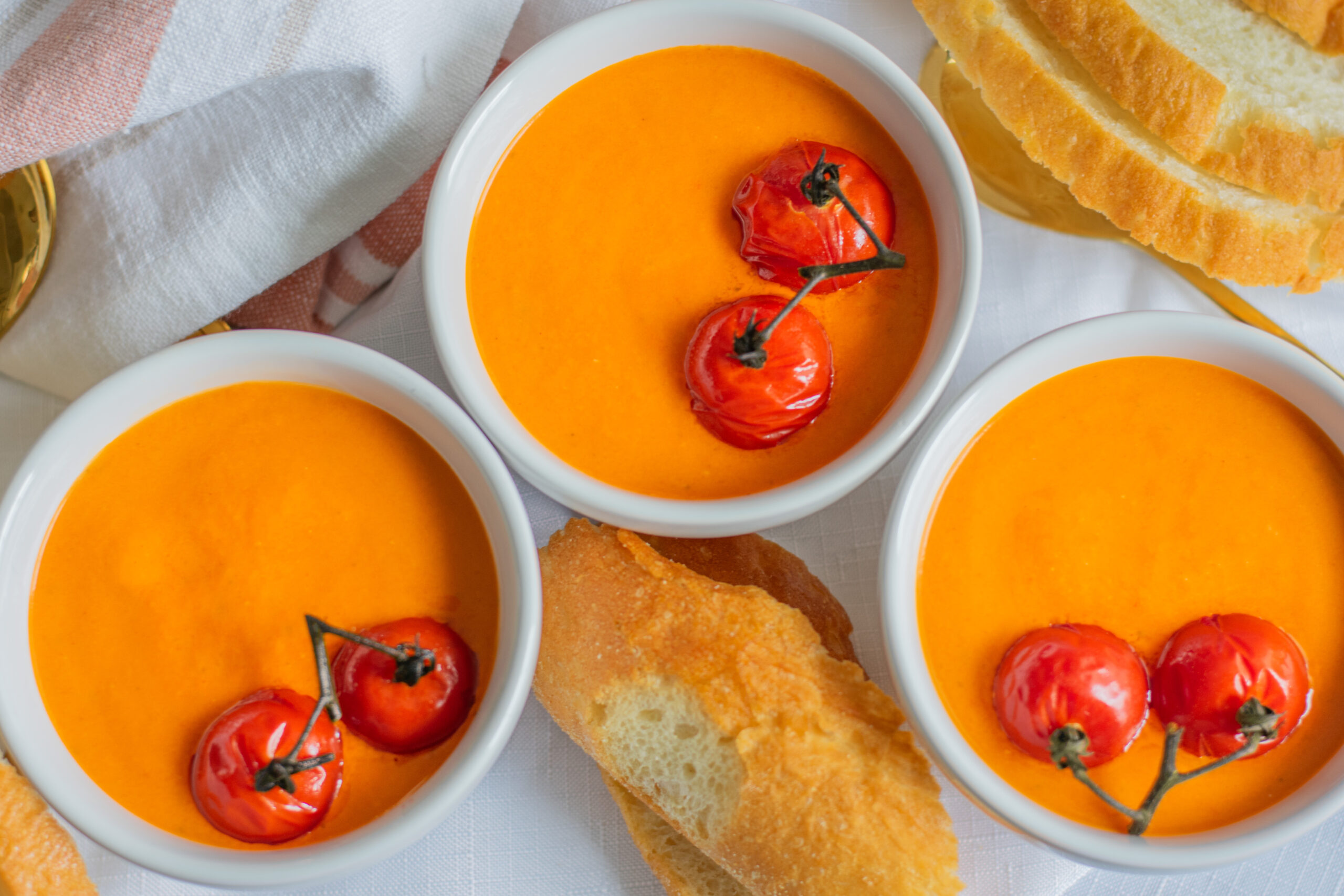 Delicious homemade roasted tomato soup served with crusty bread, topped with fresh herbs and a swirl of cream—perfect for cozy meals and comfort food lovers.