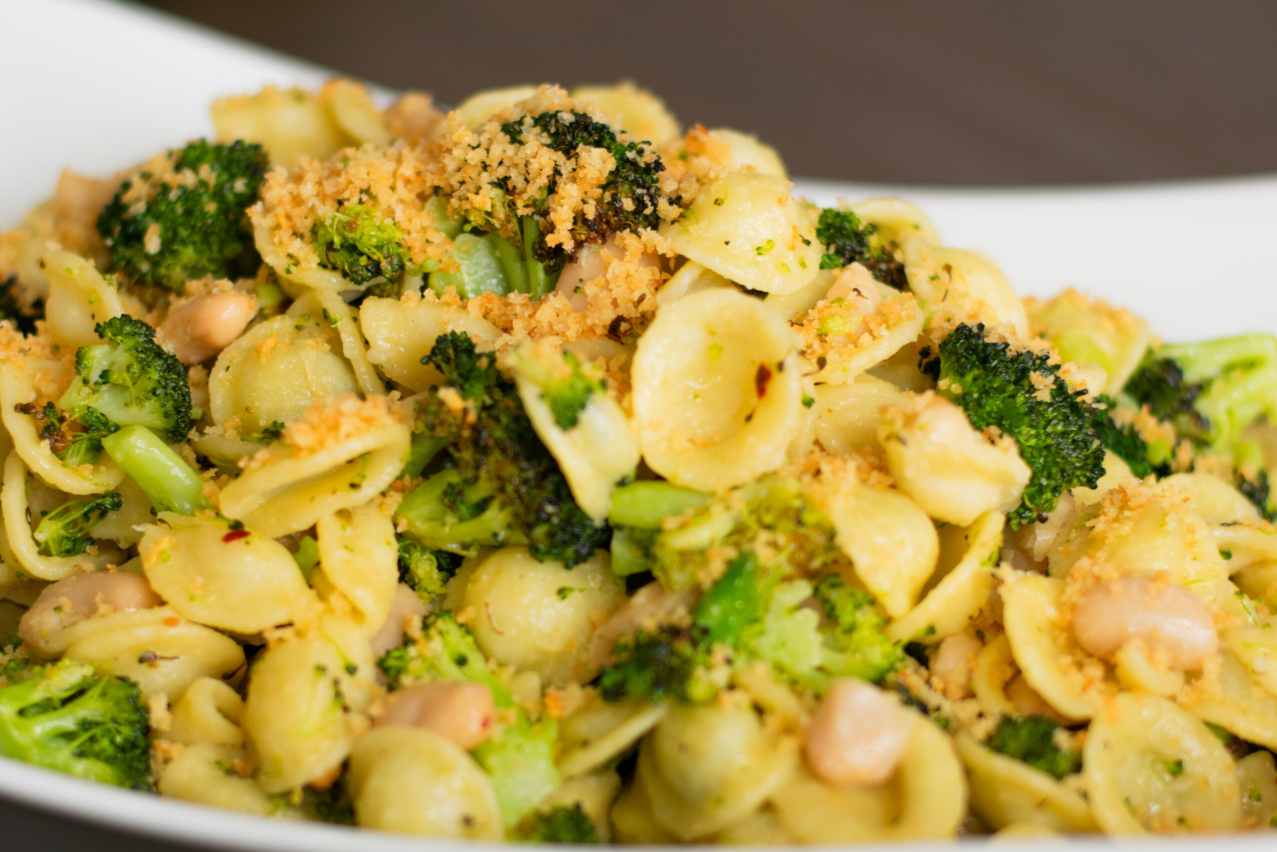 A dish piled high with orecchiette pasta, roasted broccoli, and golden toasted breadcrumbs, showcasing a vibrant and hearty Italian-inspired meal.