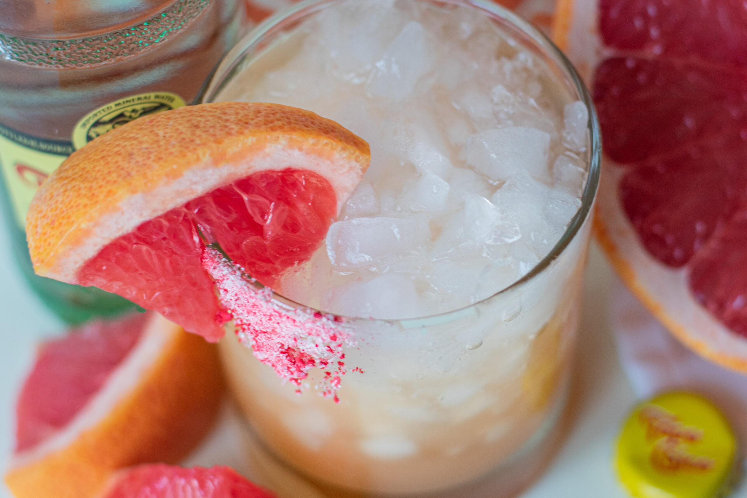 Refreshing Paloma mocktail made with ruby red grapefruit, fizzy mineral water, and agave, served in a glass with a salty-sweet rim.