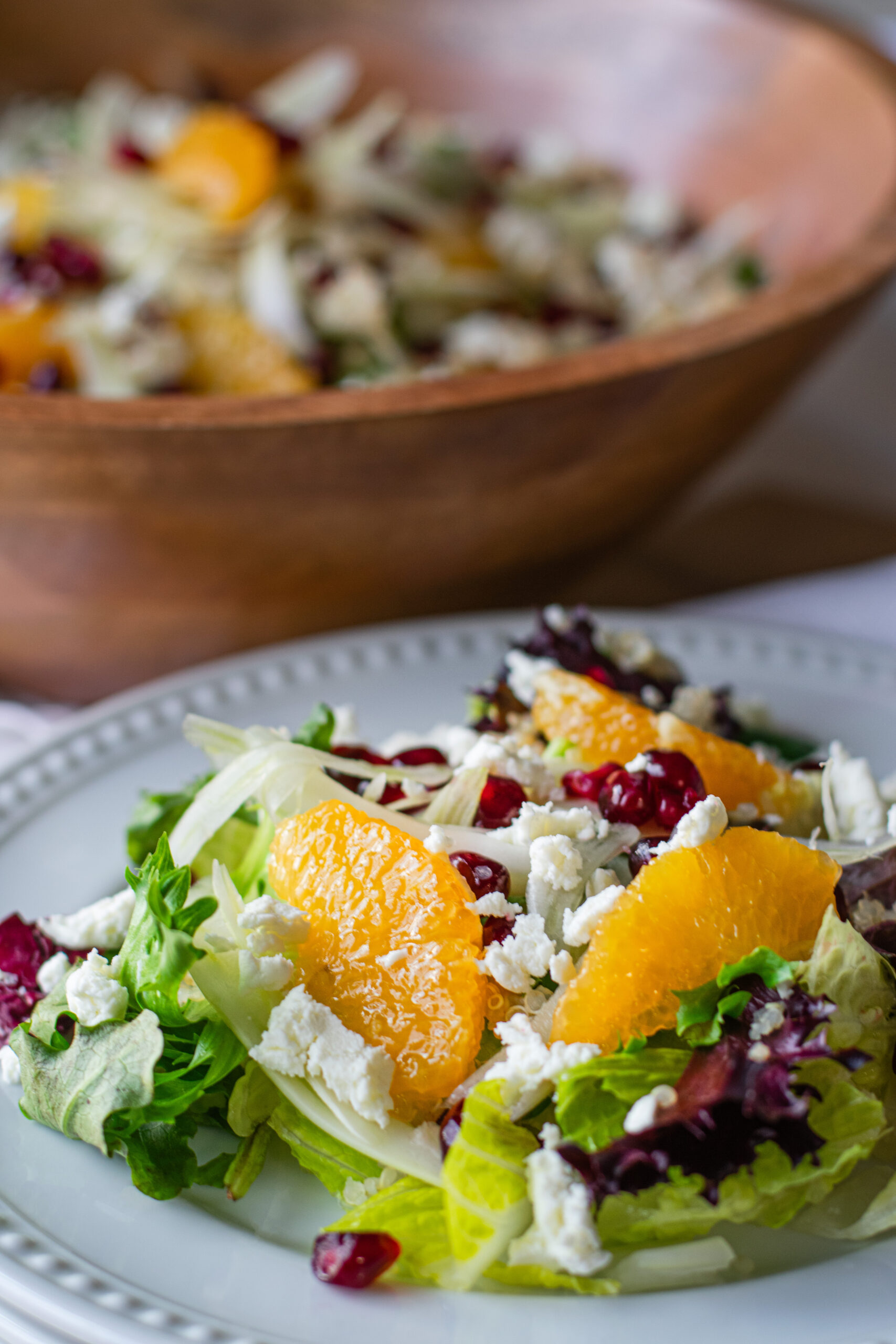 Vibrant citrus fennel salad with pomegranate gems served in a large acacia wood bowl, showcasing fresh, colorful ingredients and a homemade vinaigrette