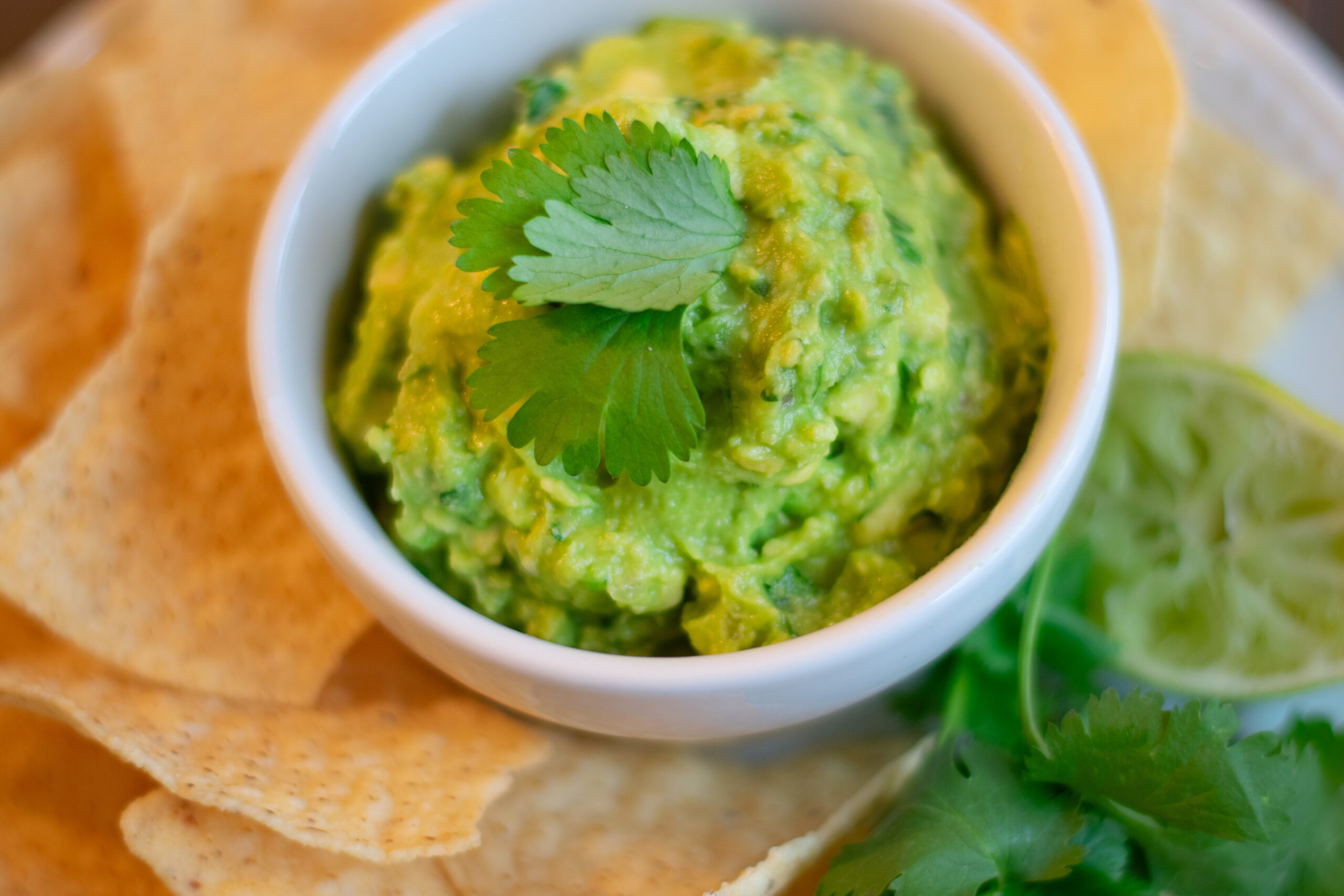 Easy Guacamole with a Cilantro Leaf garnish and Lime