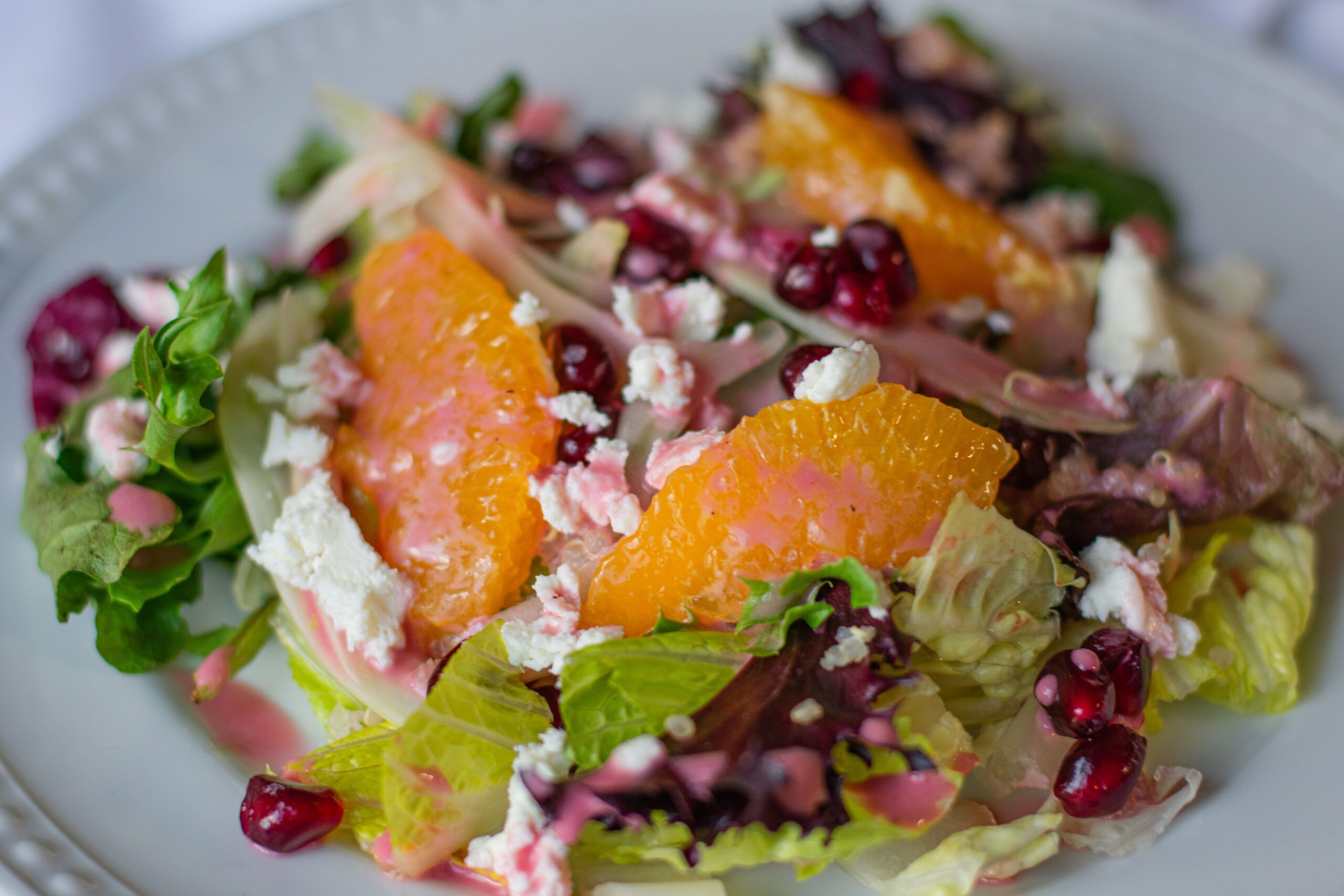 Vibrant citrus fennel salad with pomegranate gems served in a large acacia wood bowl, showcasing fresh, colorful ingredients and a homemade vinaigrette