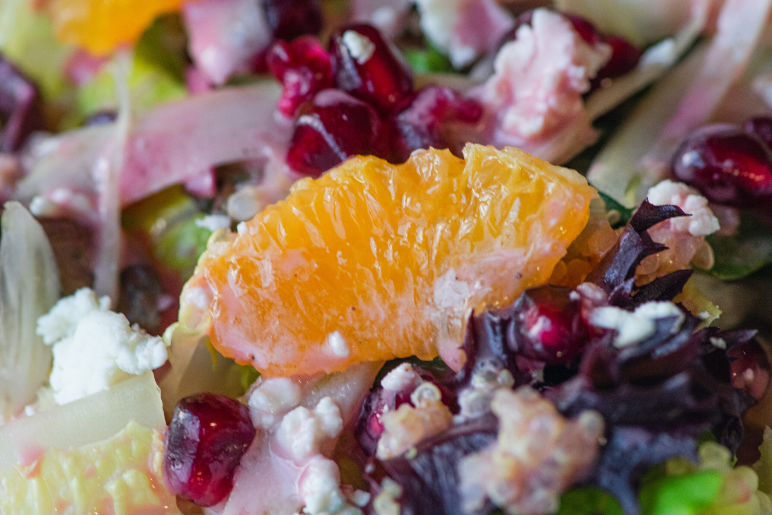 Vibrant citrus fennel salad with pomegranate gems served in a large acacia wood bowl, showcasing fresh, colorful ingredients and a homemade vinaigrette