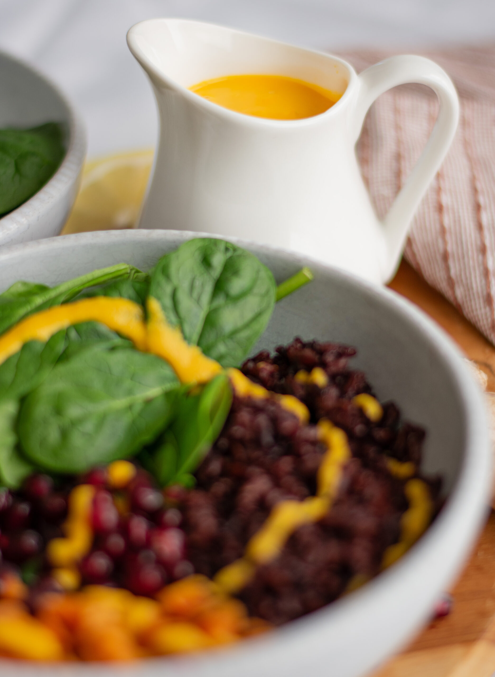 Winter Glow Buddha Bowl with black rice, roasted sweet potatoes, pomegranate seeds, and a drizzle of tangy dressing. A colorful and healthy meal for mindful eating. 