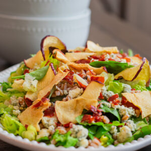 Colorful apple salad with farro, crispy prosciutto chips, and fresh greens, drizzled with a apple cider vinaigrette dressing