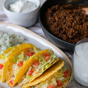 Vegetarian tacos served alongside flavorful lentil filling, topped with crisp lettuce and fresh tomatoes, with a refreshing margarita on the side.