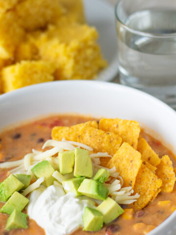 Creamy Vegetarian Tortilla Soup with Avocado Cheese Sour Cream and Tortilla Chips near cornbread