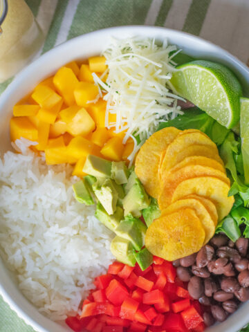 A vibrant Cuban Salad Bowl with avocado, black beans, mango, Manchego cheese, and fresh greens drizzled with lime vinaigrette.