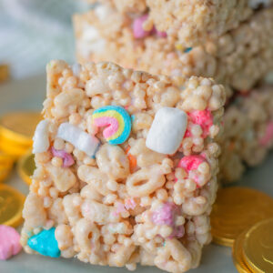 Lucky Charms Cereal Rice Krispie Treat Bars with Rainbow and Colorful Marshmallows near a pile of krispie treats