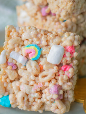 Lucky Charms Cereal Rice Krispie Treat Bars with Rainbow and Colorful Marshmallows near a pile of krispie treats