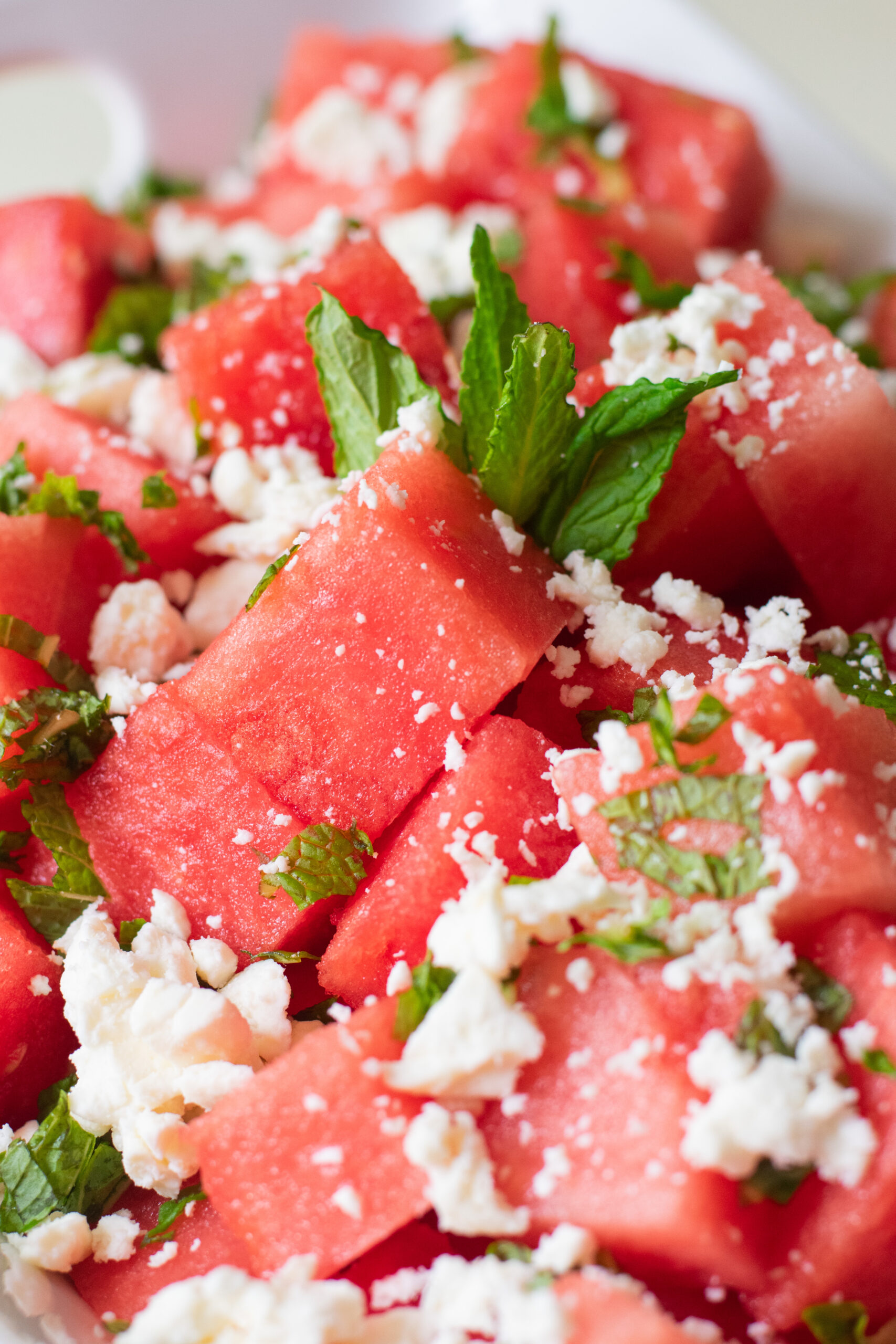 Close-up of juicy watermelon feta salad with fresh mint leaves and crumbled feta