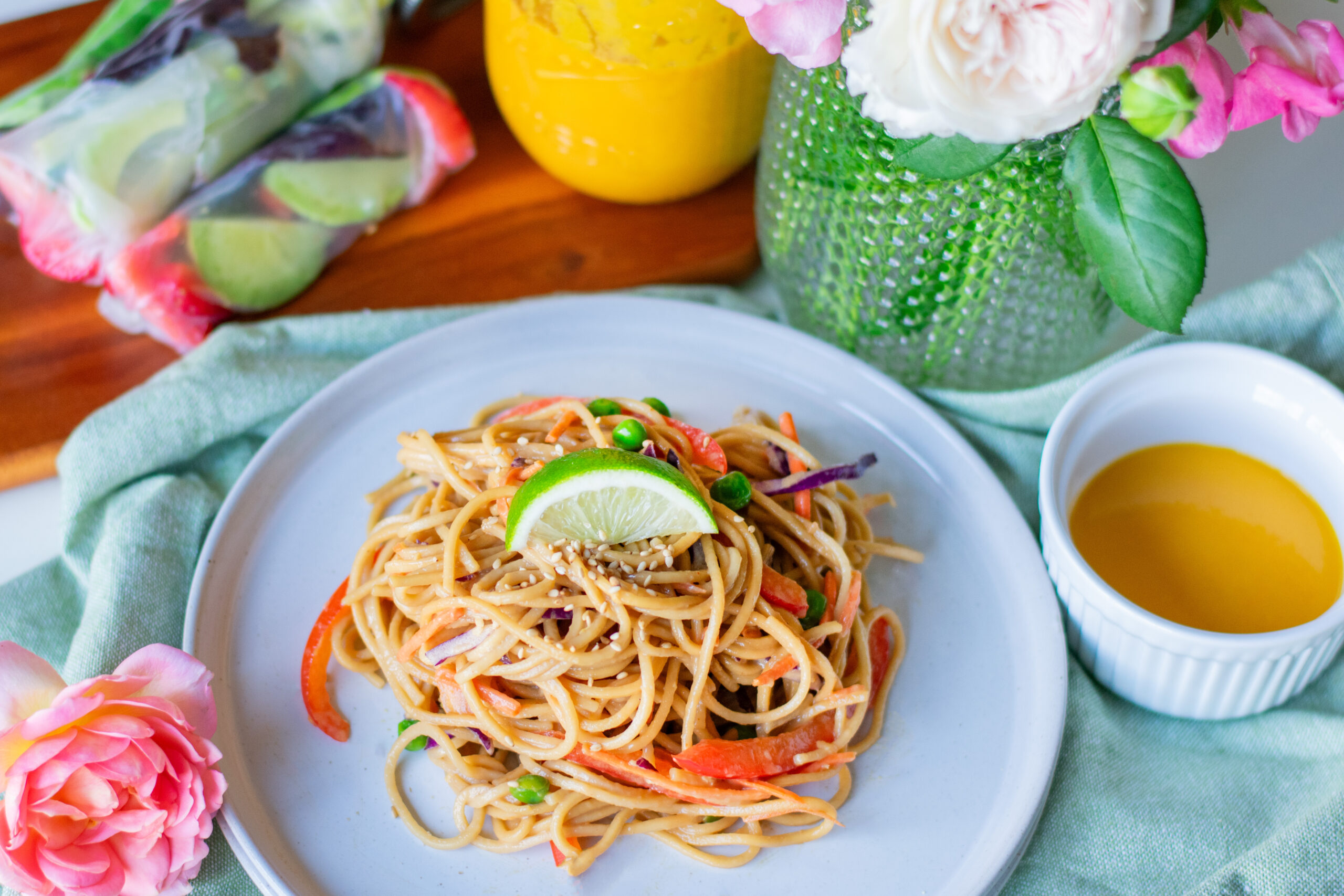 Cold vegetable lo mein noodles served next to rice wrapper spring rolls with fresh flowers from the garden