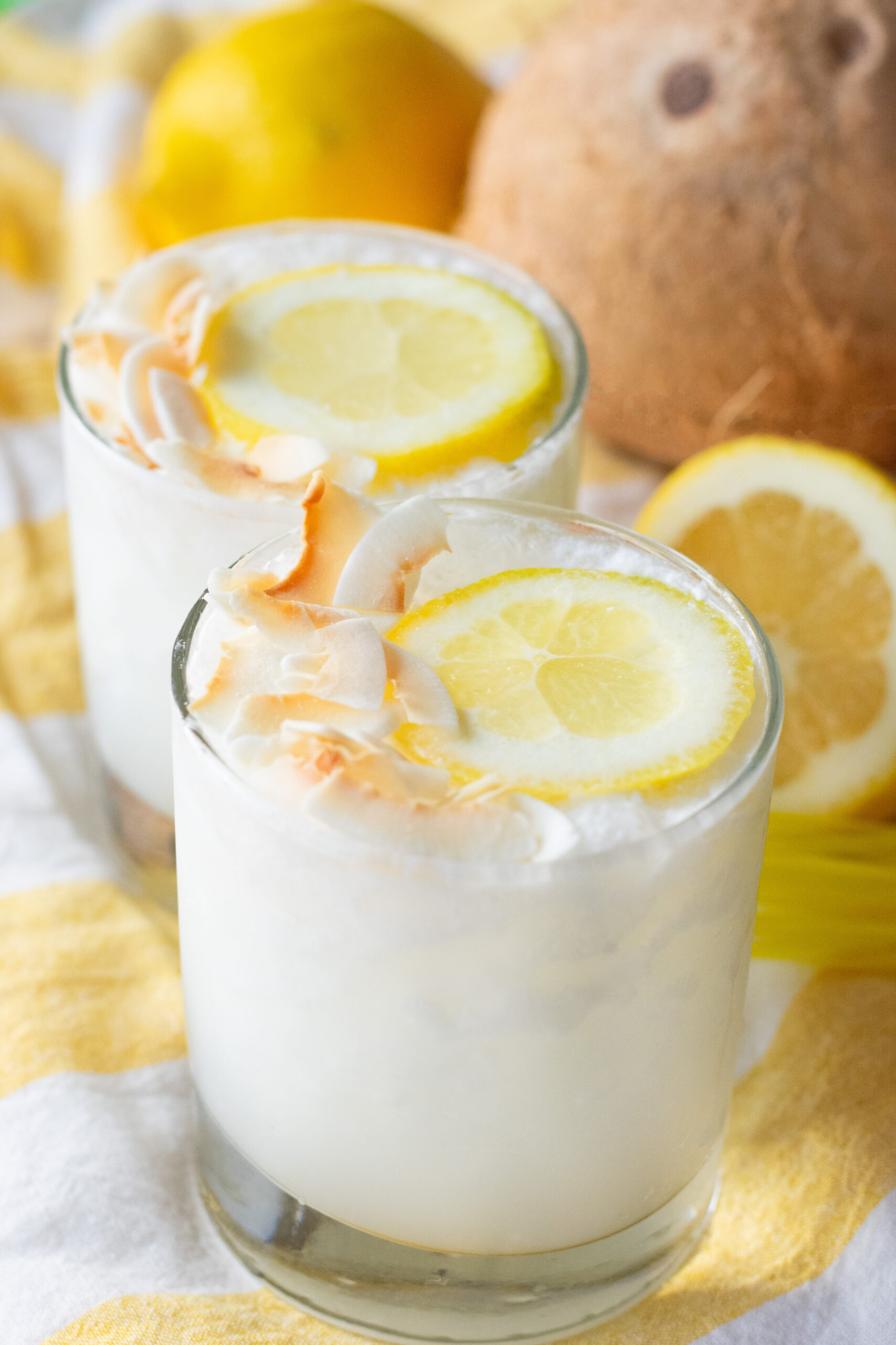 Close-up of a creamy Lemoncoco drink topped with a lemon slice and toasted coconut flakes