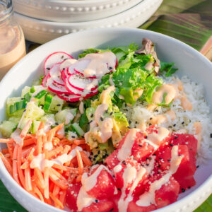 Fresh watermelon poke bowl with rice, avocado, and sesame seeds in a white bowl.