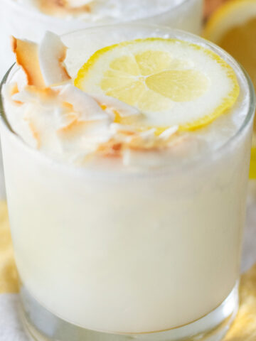 Close-up of a creamy Lemoncoco drink garnished with a lemon slice and toasted coconut flakes on top