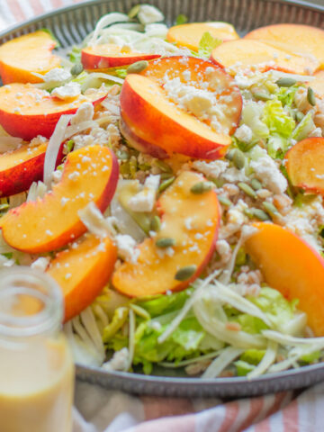 Overhead view of peach fennel salad on a round plate with farro and hot honey peach nectar dressing