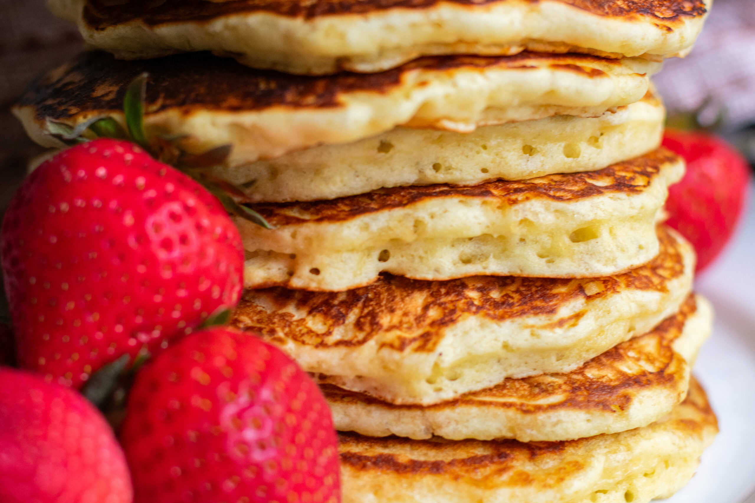 Fluffy pancake stack with fresh strawberries on the side.