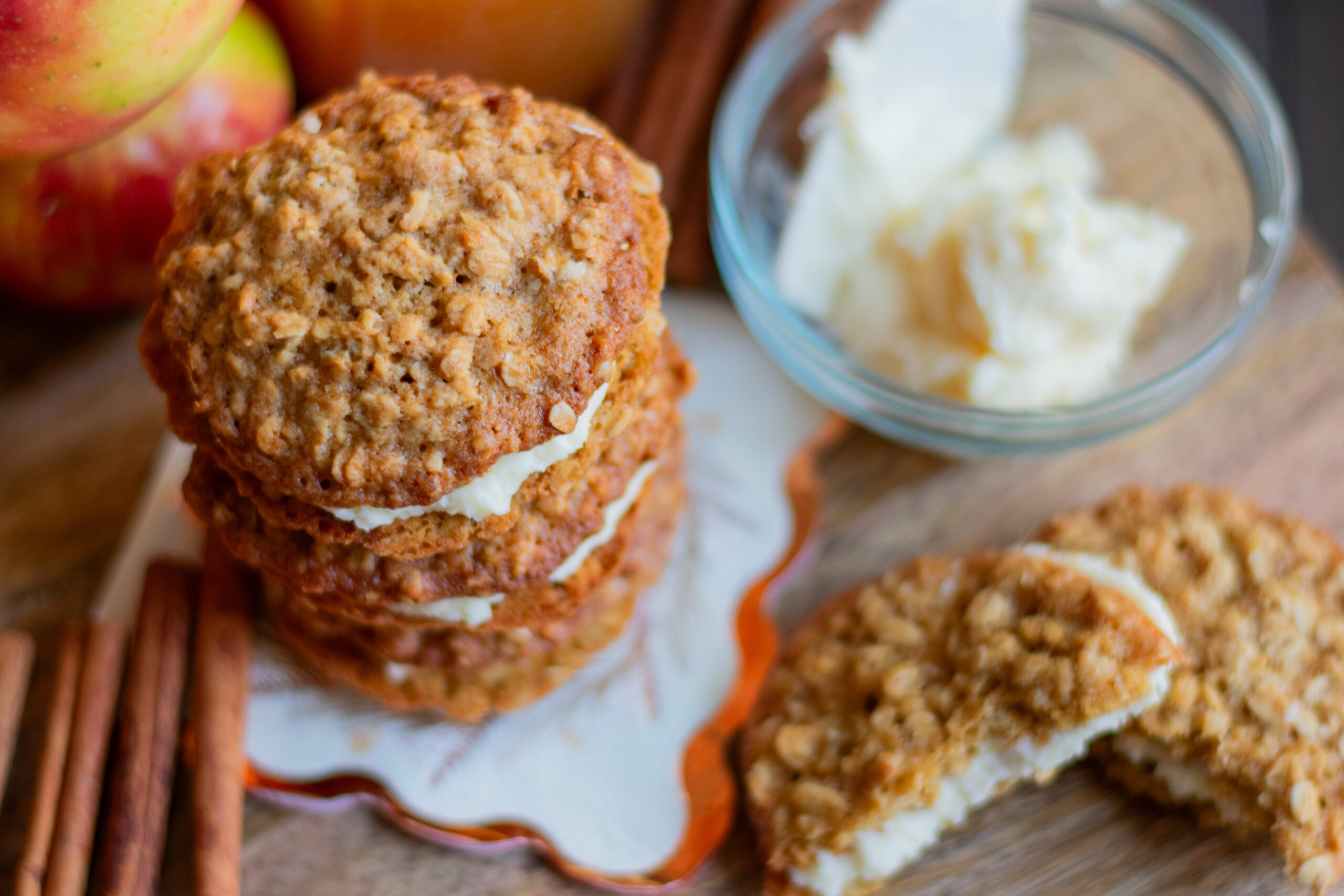 Overhead view of stacked apple cider oatmeal cream pies with frosting and cinnamon sticks