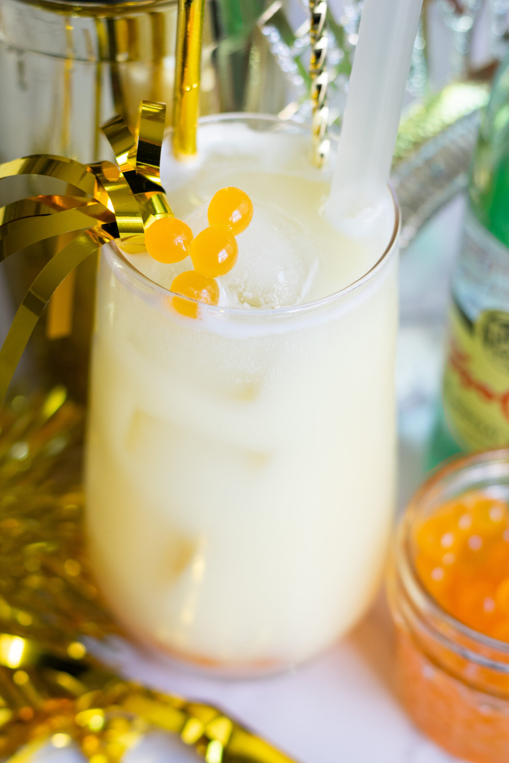 Mango popping boba drink with coconut water, pineapple juice, and sparkling water in a clear glass