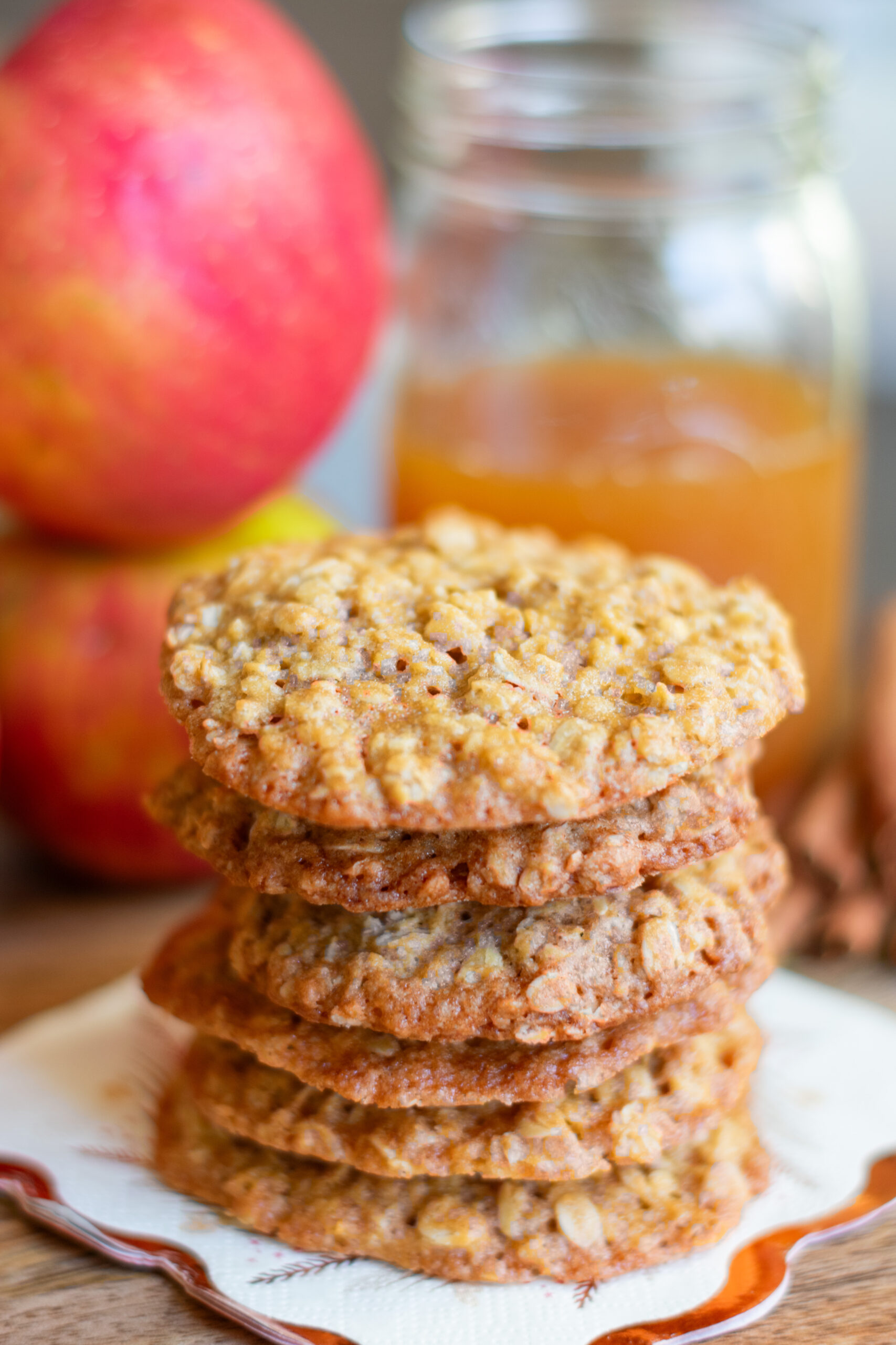 Apple cider oatmeal cookies stacked with apples and cider