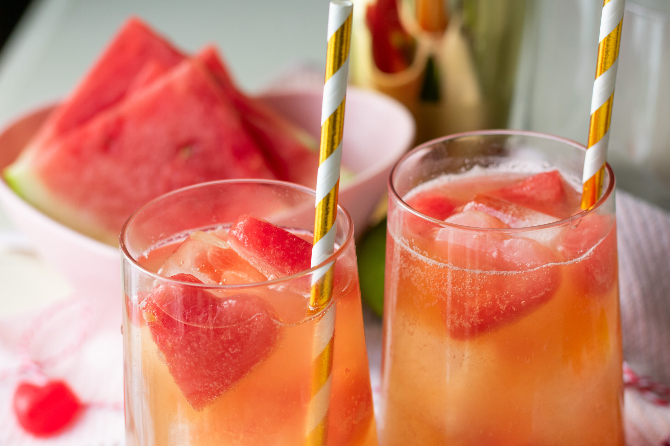 Pink popping boba mocktail with watermelon heart ice cubes and fizzy bubbles with gold and white straws