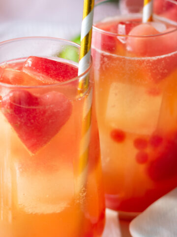 Pink popping boba mocktail with juice, watermelon heart ice cubes, and bubbles