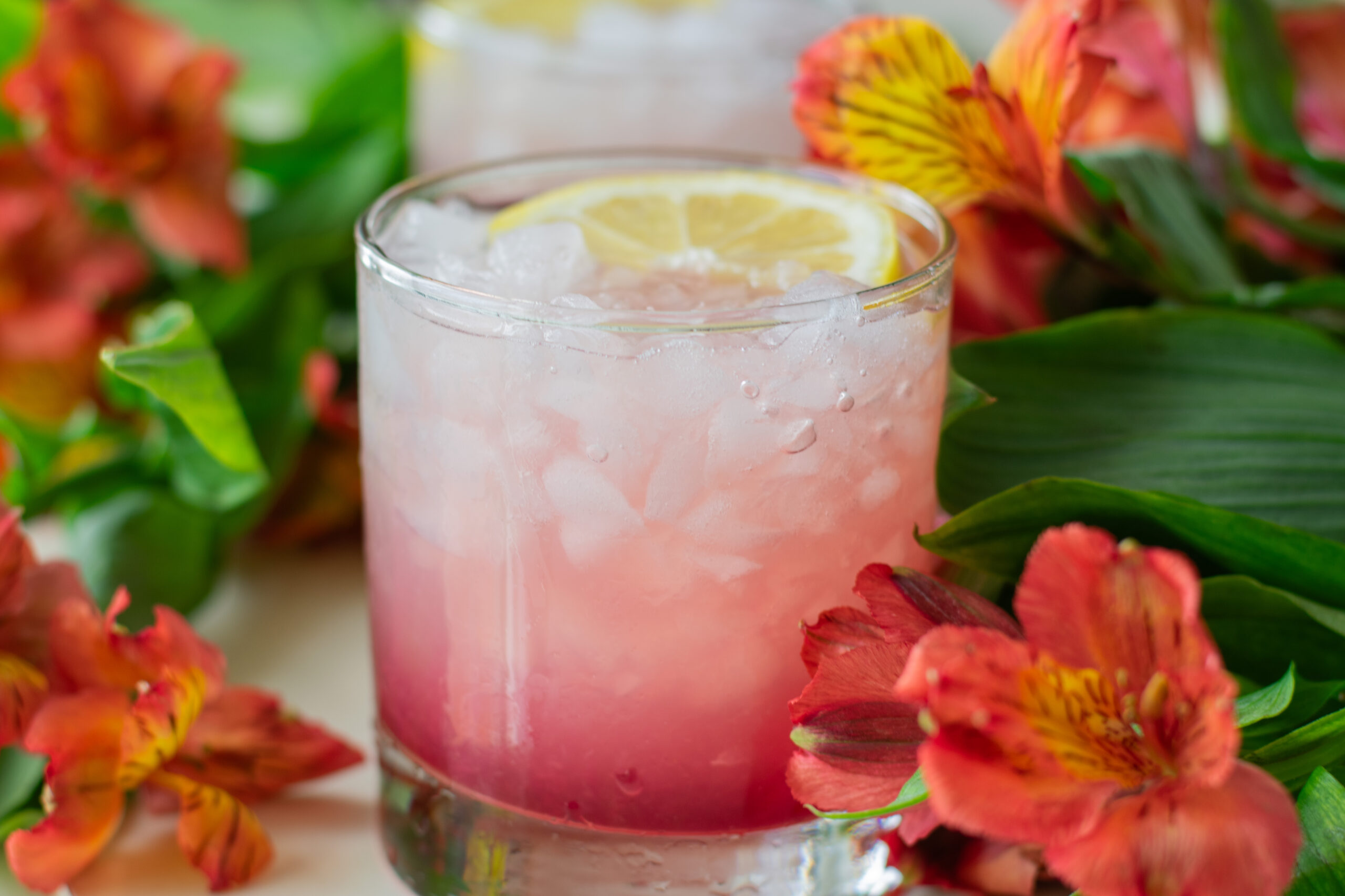 azalea mocktail with pomegranate juice and lemon garnish over crushed ice in glass
