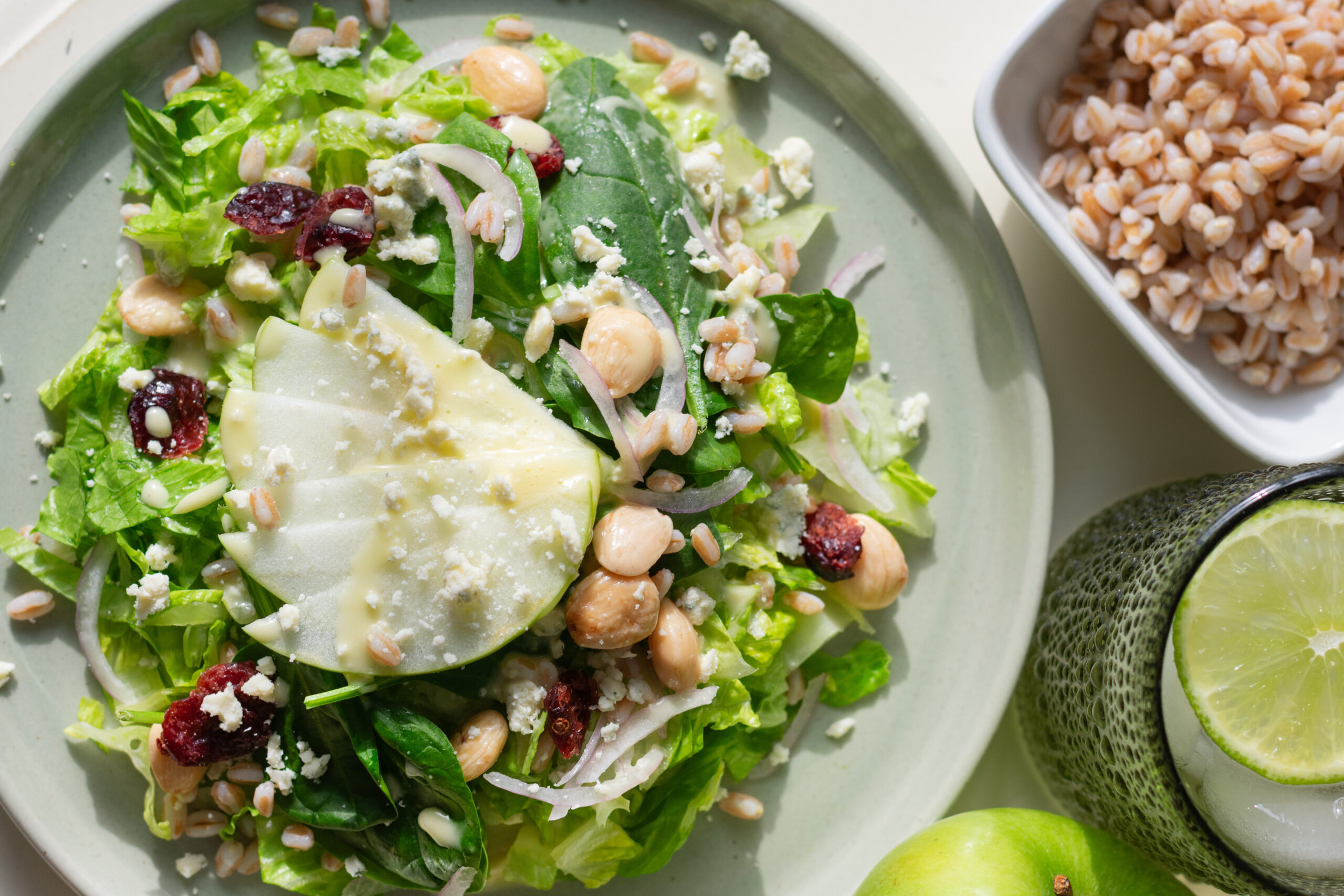 Overhead view of green apple farro salad with gorgonzola, cranberries, and marcona almonds on a serving platter